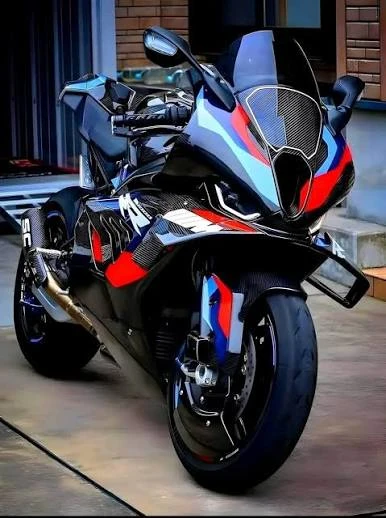 Full carbon BMW M 1000 RR in black with blue and red M accents, front three-quarter view
